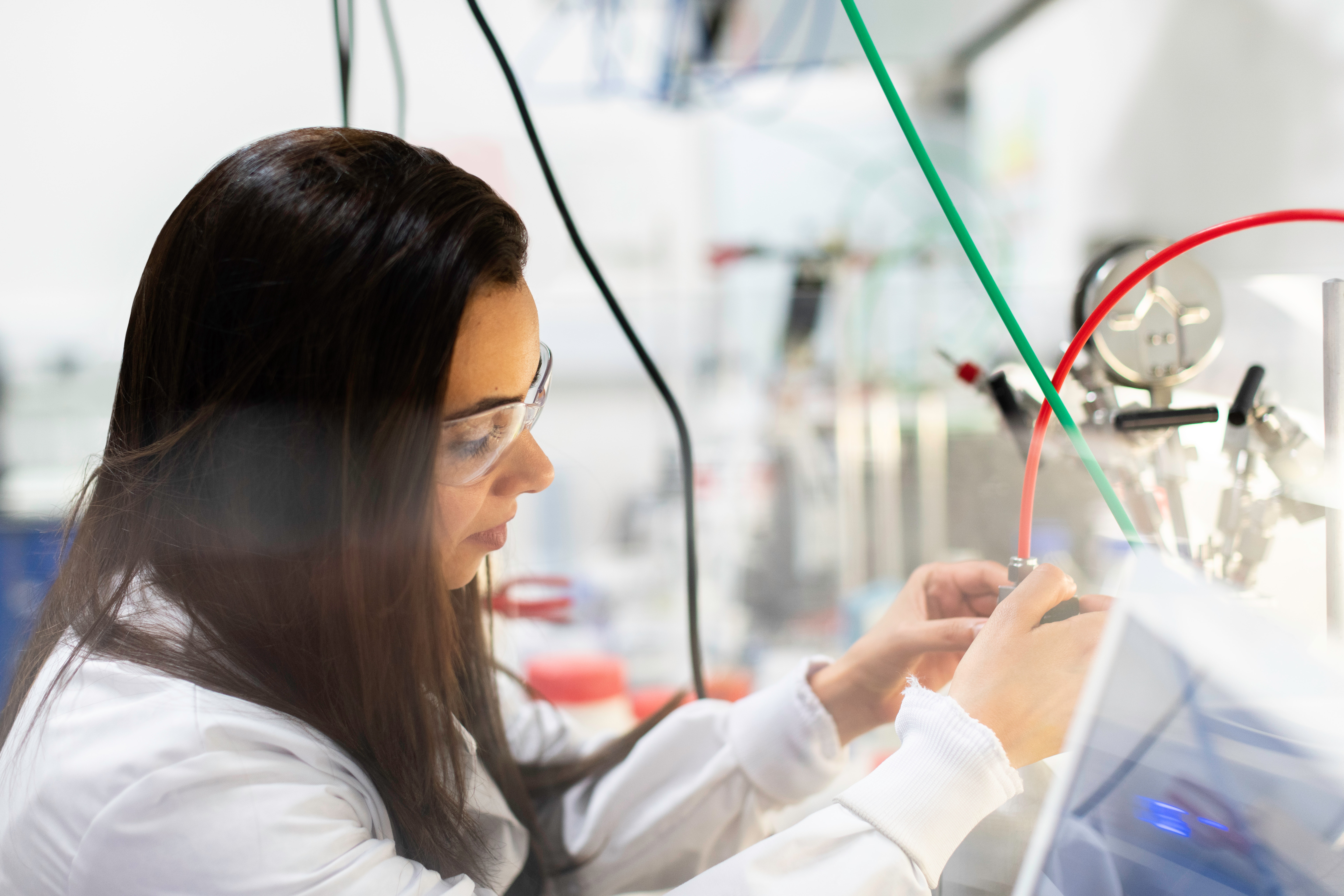 person in a lab looking at red and green wires